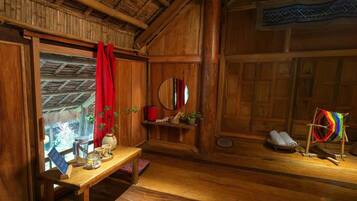 Une pièce rustique avec des murs en bois, une table en bois, un rideau rouge, un miroir et un objet tissé aux couleurs vives, posé sur un présentoir.