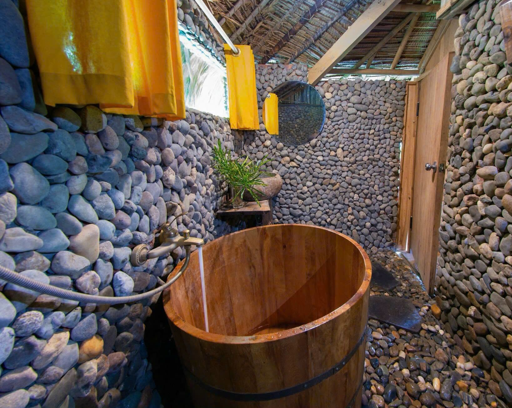 Un tonneau en bois dans une pièce aux murs de pierre, avec une petite plante et un objet jaune accroché au mur.
