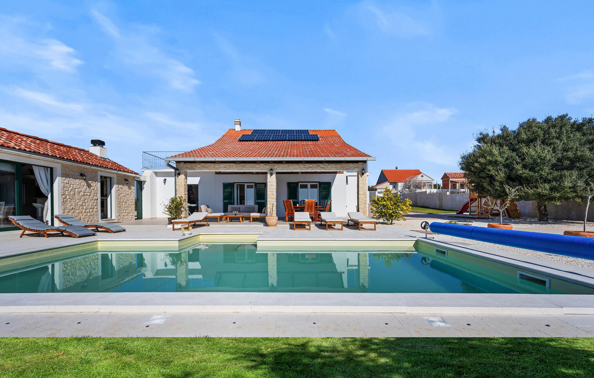 Une maison avec une piscine, un espace salon extérieur et un panneau solaire sur le toit.