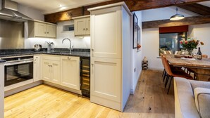 Une cuisine moderne avec des meubles blancs, un four encastré et un coin repas comprenant une table et des chaises en bois.