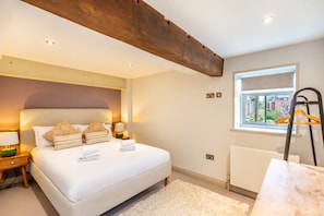 A bedroom with a large bed, bedside lamps, a window with a view, and a radiator.