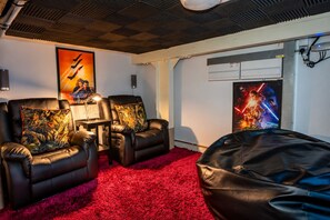 A room with two leather recliners, a red carpet, a poster of a movie, and a large bean bag.