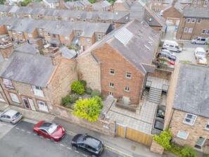 A residential area with terraced houses, a narrow street, and parked cars.