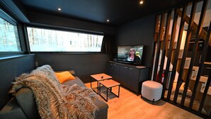 Una sala moderna con un sofá, una mesita, un televisor y una escalera.