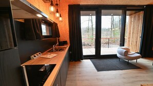 Una cocina moderna con encimera de madera, horno integrado y un amplio ventanal con cortinas.