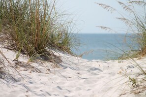 A sandy beach with sparse vegetation and a clear view of the ocean. - Sea Sway : Modern 4‑Bed Townhouse with Sea Views in Rhosneigr | Managed by Anglesey Holiday Lettings (Rhosneigr)