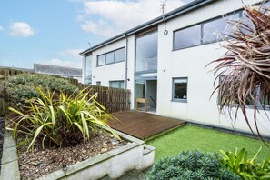 Enclosed rear garden with decking and planted borders, outdoor space at pet-friendly upside-down holiday home in Rhosneigr, Anglesey