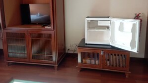 A compact living space with a wooden cabinet containing a television and a small refrigerator. - Alpine Premium Water Chalet 2  (Port Dickson)