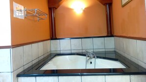 A bathroom with a freestanding bathtub, tiled walls, and a wooden arch above the tub. - Alpine Premium Water Chalet 2  (Port Dickson)