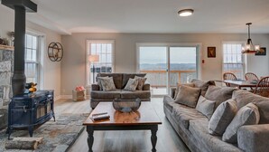A spacious living room with a stone fireplace, a large sofa set, and a dining area with a view of the outdoors. - Stunning Views | Hot Tub | Pets (Carroll)