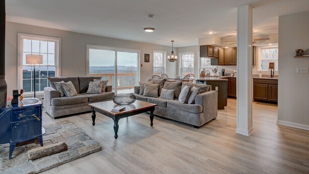 A spacious living room with a fireplace, two sofas, a coffee table, and a view of the outdoors. - Stunning Views | Hot Tub | Pets (Carroll)