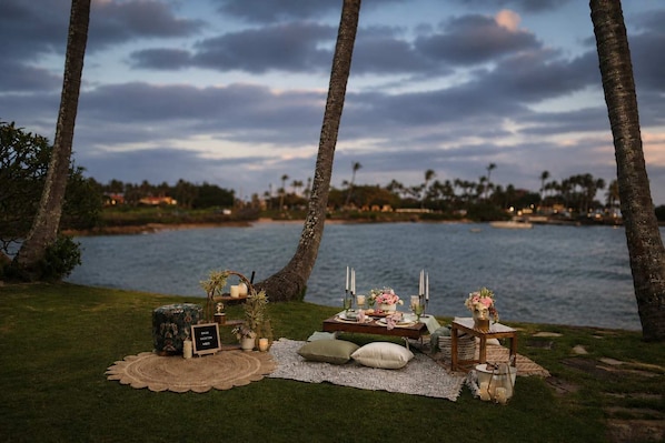 A beachside picnic setup with a table, candles, and a sign that reads 'Vacation Vibes.'