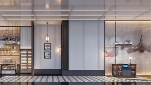 Een moderne hotellobby met een bar, zitplaatsen en een decoratieve muur met een traditioneel ontwerp.