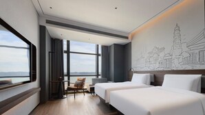 Een hotelkamer met twee bedden en uitzicht op de stad, met een groot raam.