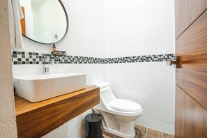Un bagno moderno con lavandino bianco, mobile contenitore in legno e servizi igienici.