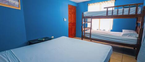 Una habitación con literas, una cama individual, un ventilador de techo y una puerta.