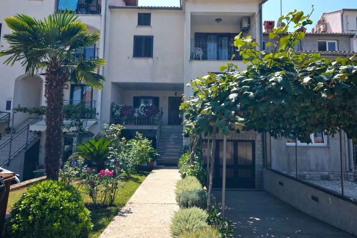 A courtyard with a central pathway, surrounded by buildings with balconies and a palm tree.