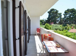 Enjoy dining al fresco with a view of lush greenery and distant buildings from this balcony.