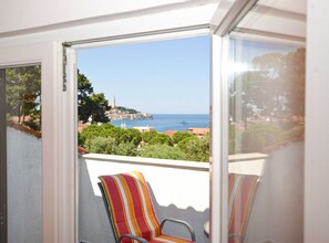 Enjoy the view of the coastal town from the balcony with a chair and table.
