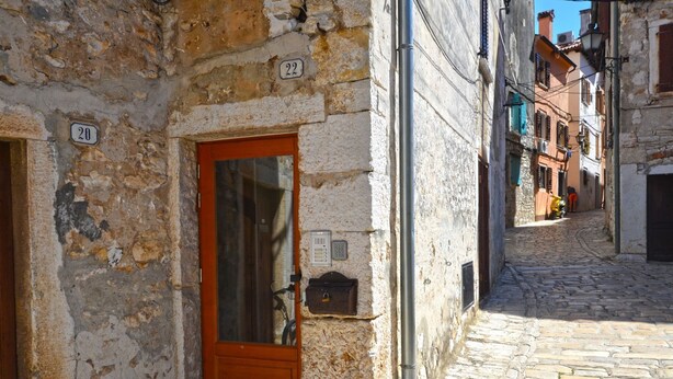 Ένας στενός, λιθόστρωτος δρόμος με ένα πέτρινο κτίριο που διαθέτει μια ξύλινη πόρτα και ένα κουτί επιστολών.