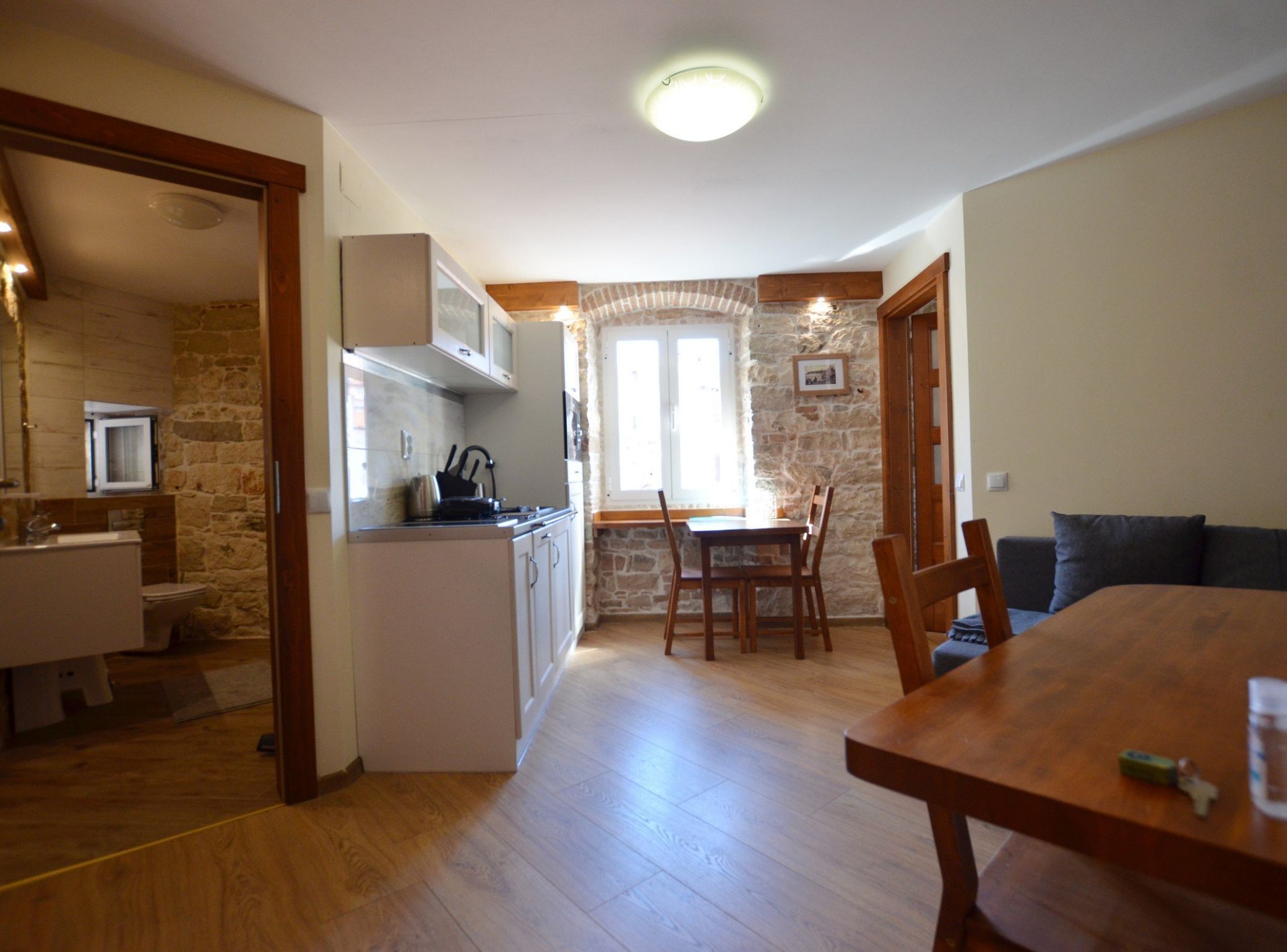 A compact kitchen with a dining area, stone walls, and a wooden dining table.