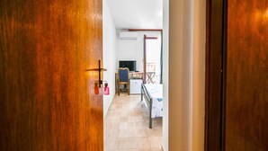 Un couloir menant à une chambre à coucher équipée d’un lit, d’un bureau et d’une chaise.