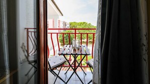 Un balcon avec une balustrade rouge, une table et une chaise.