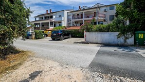 Un immeuble résidentiel doté de nombreux balcons, d’une allée pavée et d’une voiture garée.