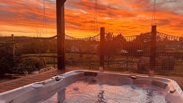 A hot tub with a wooden deck and a netted enclosure, set against a sunset backdrop. - Nature-themed vacation rental with a private spa and fully air-conditioned pool (Saint-Astier)