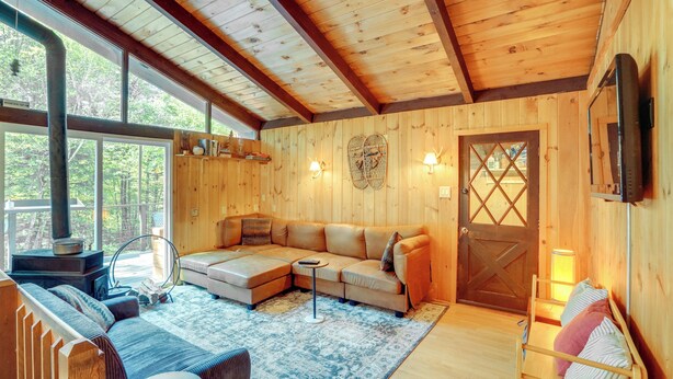 A cozy cabin interior with a wooden ceiling, a sectional sofa, a small table, and a fireplace. - 6 Mi to Slopes: Forest-View Haven in West Dover! (West Dover)