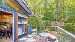 A wooden deck with a dining area, a kitchen with modern appliances, and a view of a forest. - 6 Mi to Slopes: Forest-View Haven in West Dover! (West Dover)