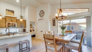 A spacious kitchen with wooden cabinets, a large island with stools, and a dining area with wooden chairs and a table. - Walk to Rainbow Lake: High Country Retreat w/ Deck (Pinetop-Lakeside)