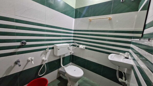 A small bathroom with a toilet, sink, and a red bucket.