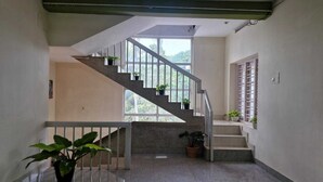 A staircase with potted plants, a window with a view of greenery, and a light-colored interior. - Akshay beach resort  (Varkala)
