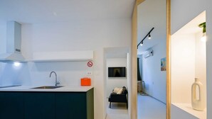 A modern kitchen with a built-in island, a dining area with a black sofa, and a mirrored wall reflecting the room. - Smart and Cozy Downtown Rovinj Nooks (Rovinj)