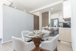 Cozy living space with a dining area and kitchenette, featuring a glass-top table and four chairs.