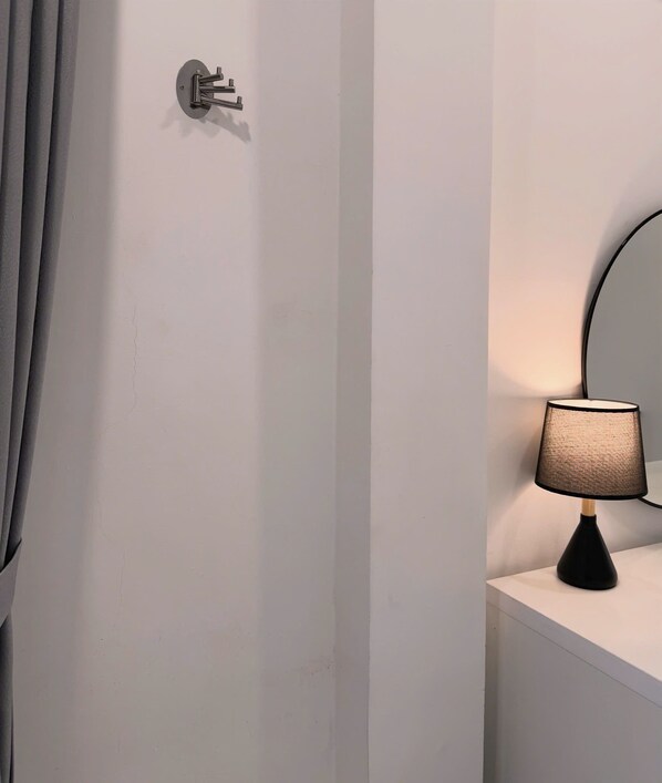 Un baño moderno con un perchero, un espejo redondo y una lámpara de mesa.