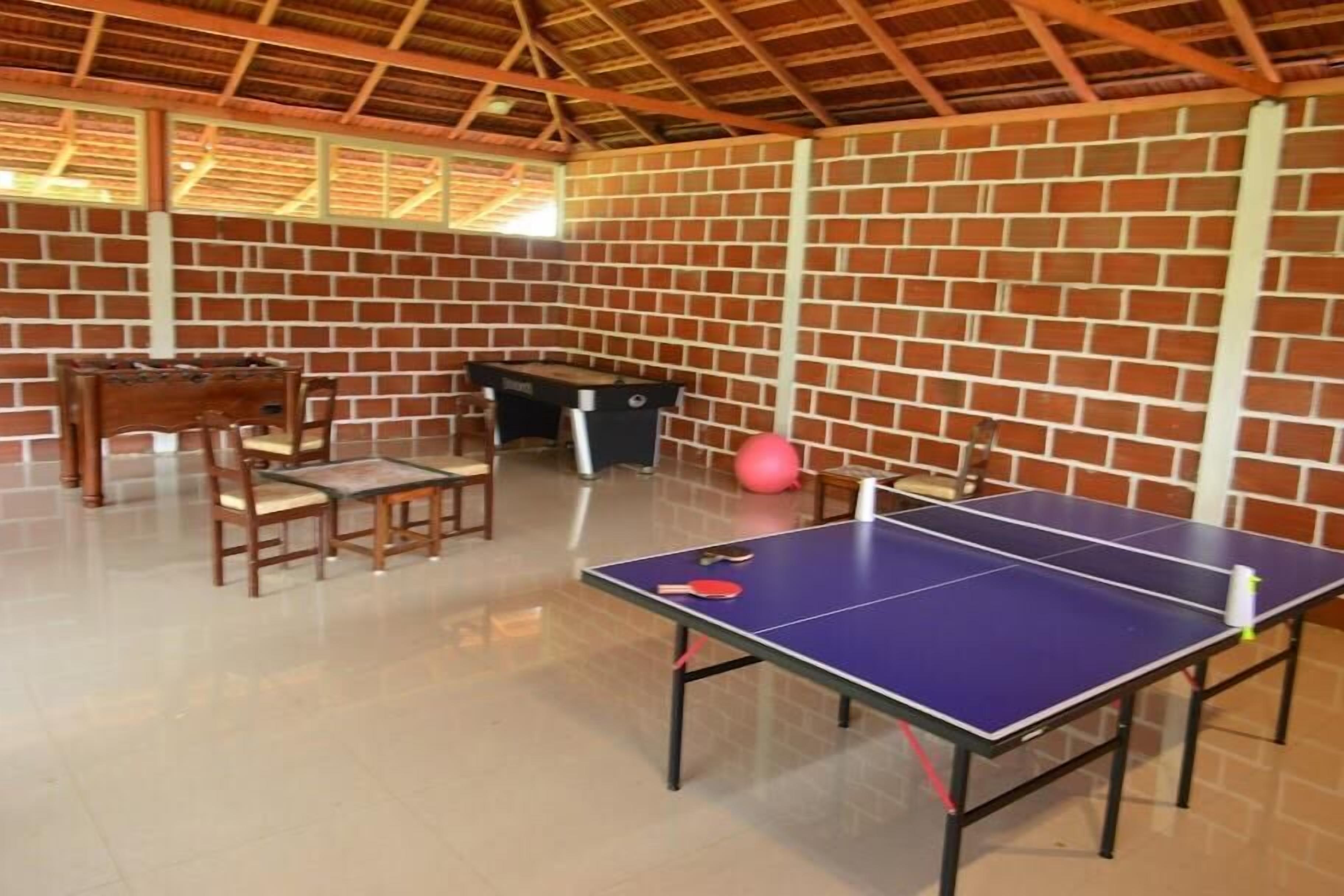 Una habitación con mesa de ping pong, sillas, mesa de fútbol y mesa de billar.