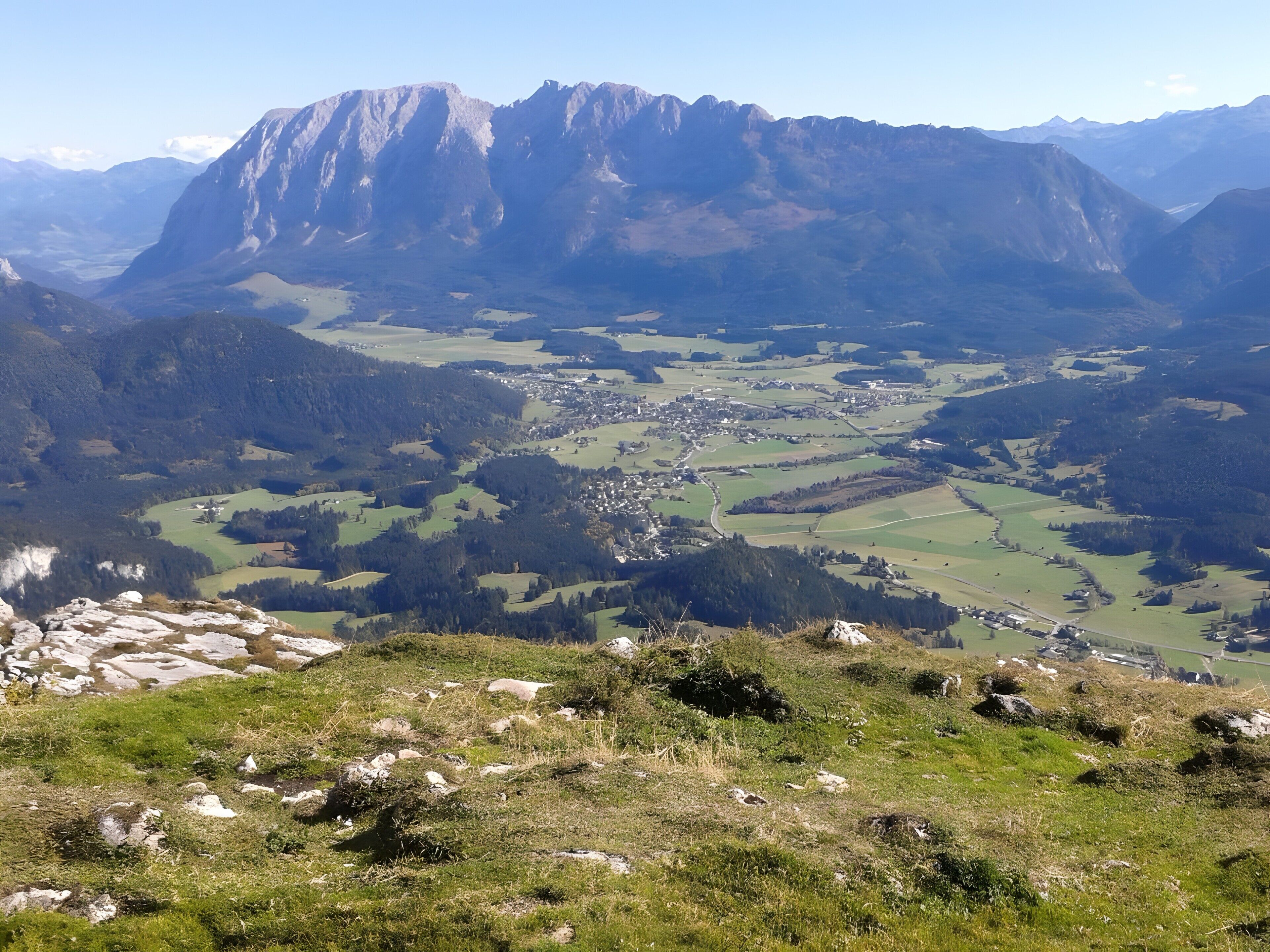 A mountainous landscape with a valley, a small town, and rocky terrain in the foreground.