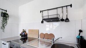 Una cocina moderna con un lavamanos de acero inoxidable, un horno empotrado y una encimera con una planta y utensilios de cocina.