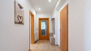 Ein Flur mit einer Holztür am Ende, einem Heizkörper und einem Wandbild.