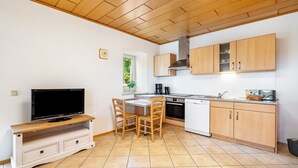 Eine Küche mit Holzausstattung, inklusive Einbauherd, Geschirrspüler und einem Fernseher auf einem Holzboden.
