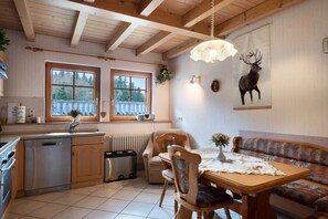 Un interno in legno con un tavolo da pranzo, sedie, un divano, un termosifone, una finestra e un quadro di un cervo appeso al muro.