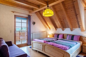 Una camera da letto con soffitto in legno, un letto con copriletto a righe, un comodino e una finestra vista.