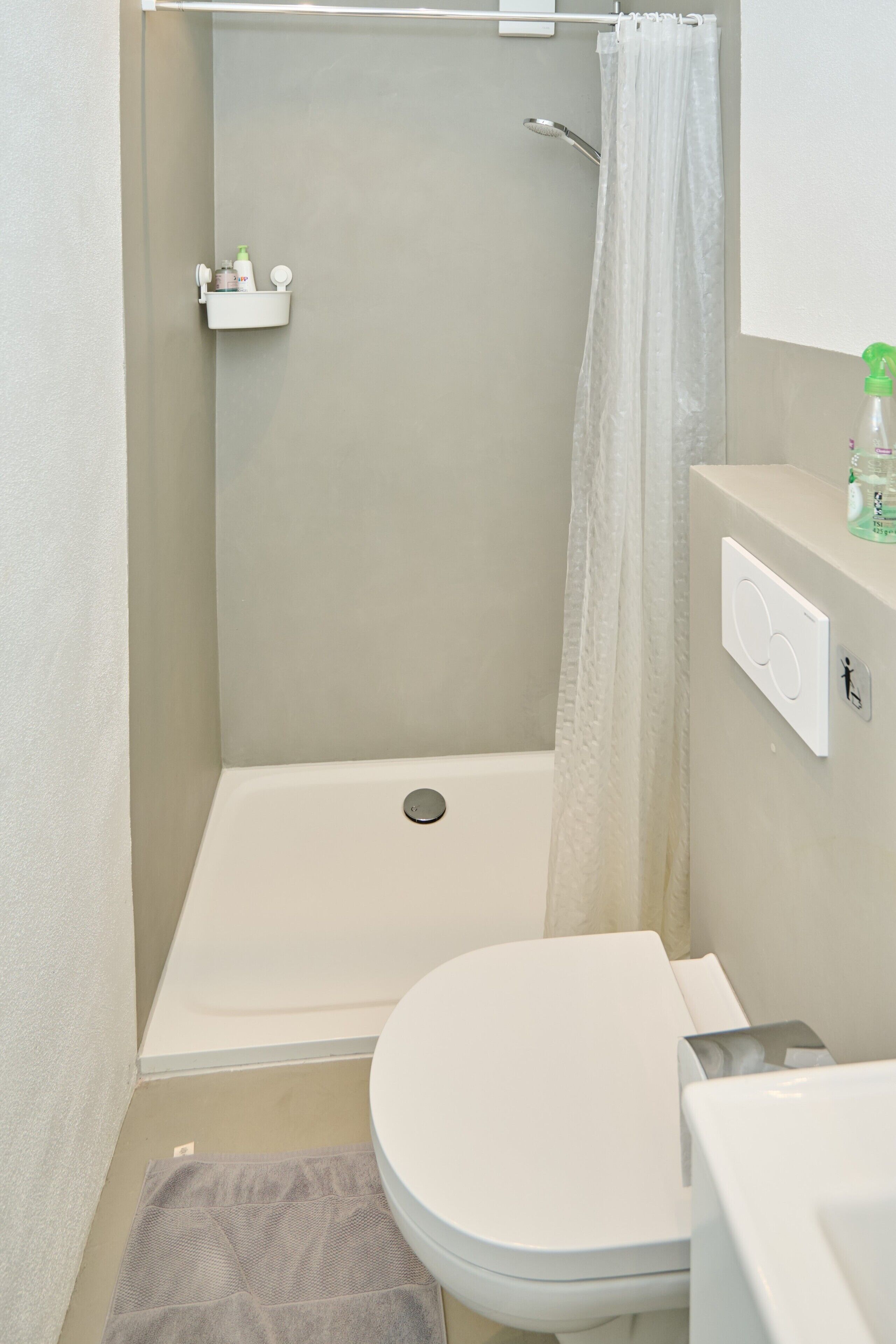 Ein Badezimmer mit Dusche, Toilette und einem Handtuch auf dem Boden.