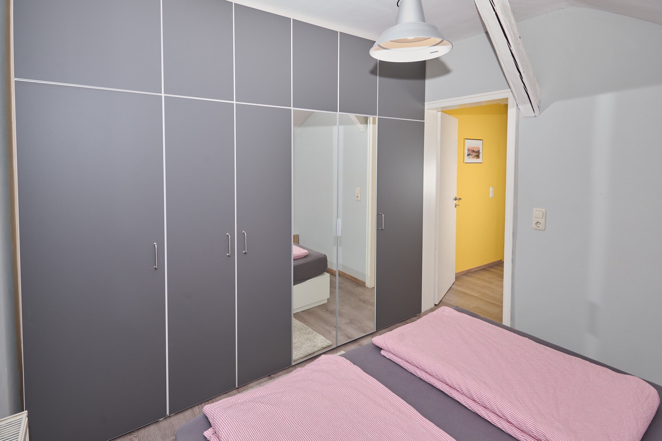 A bedroom with a bed, a wardrobe, and a mirror.
