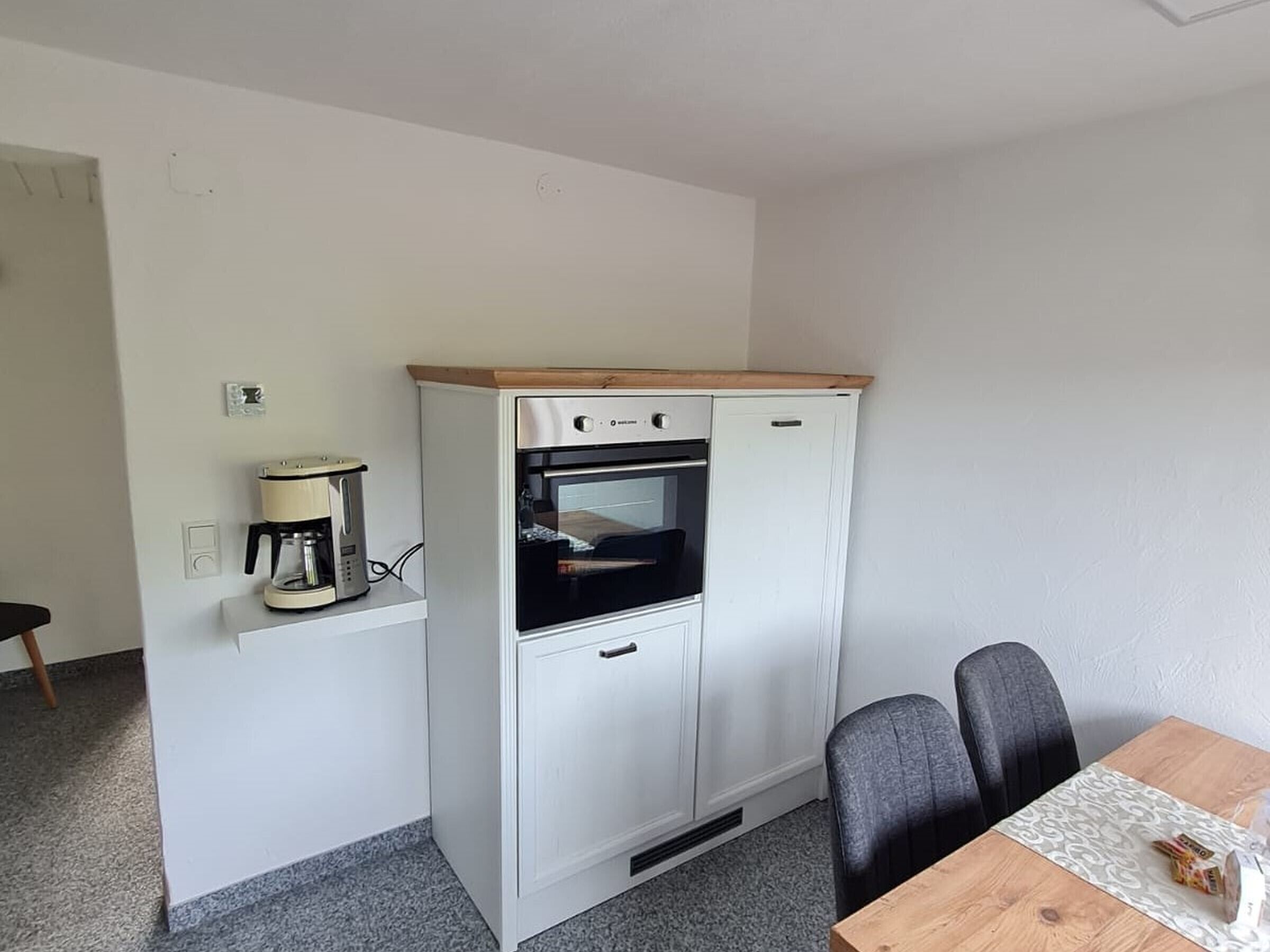 A compact kitchenette with a coffee maker, oven, and a small refrigerator.