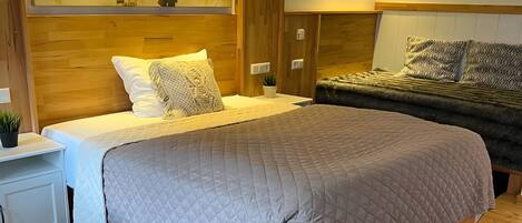 A hotel room with a large bed, a nightstand, a small table, a black rug, and a wall with a mural.