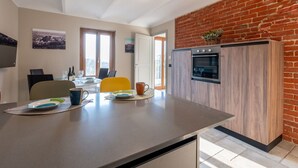 A modern kitchen with a brick wall, a dining area with a table and chairs, and a large window.