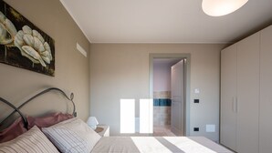 A bedroom with a bed, a nightstand, a painting, and a wardrobe.